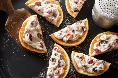 English muffin halves topped with a white smear and brown chunks