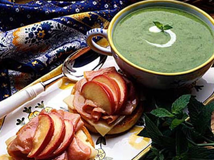 BAYS TOPPED WITH APPLE AND MEAT NEXT TO A GREEN BISQUE