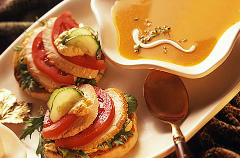 ORANGE SOUP NEXT TO BAYS TOPPED WITH TOMATO AND MEAT