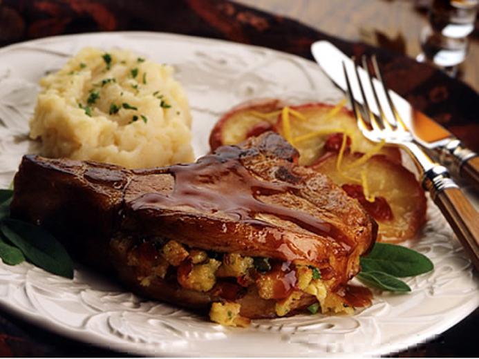 COOKED MEAT FILLED WITH DICED BAYS ON A PLATE WITH SAUTEED APPLES AND MASHED POTATOES