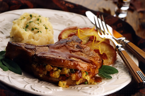 COOKED MEAT FILLED WITH DICED BAYS ON A PLATE WITH SAUTEED APPLES AND MASHED POTATOES