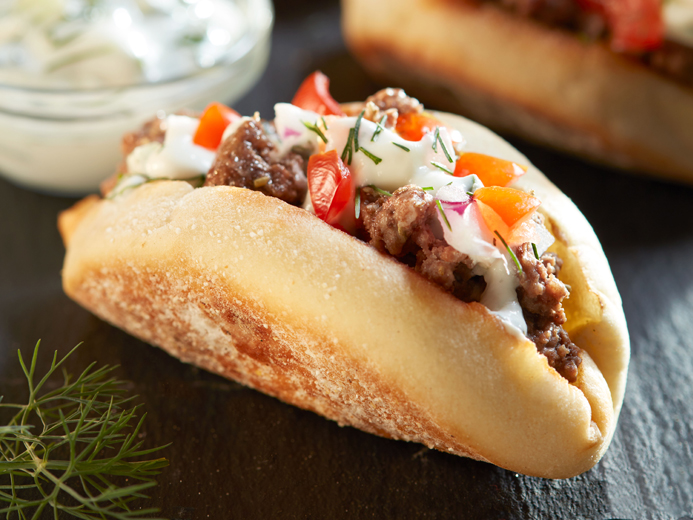 ENGLISH MUFFIN FOLDED IN HALF FILLED WITH MEAT AND TZATZIKI SAUCE