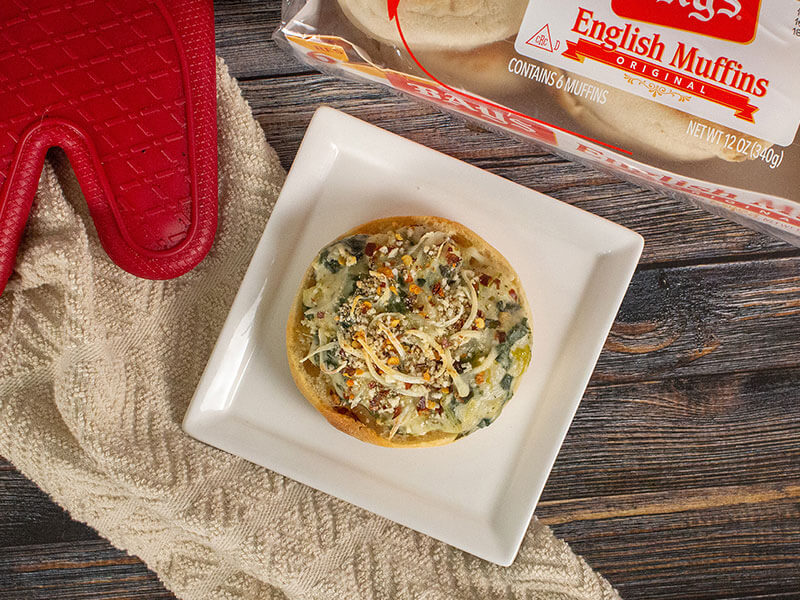 bays topped with a green and white spread and grated cheese