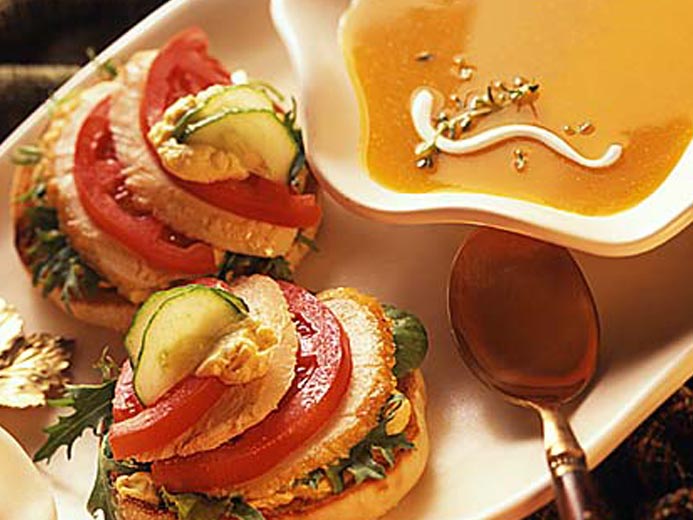 ORANGE SOUP NEXT TO BAYS TOPPED WITH TOMATO AND MEAT