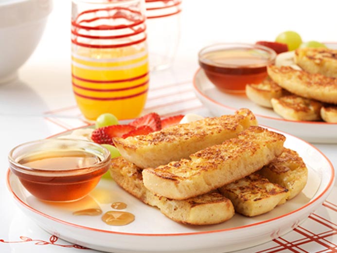 STRIPS OF BAYS STACKED ON A PLATE NEXT TO A DISH OF MAPLE SYRUP